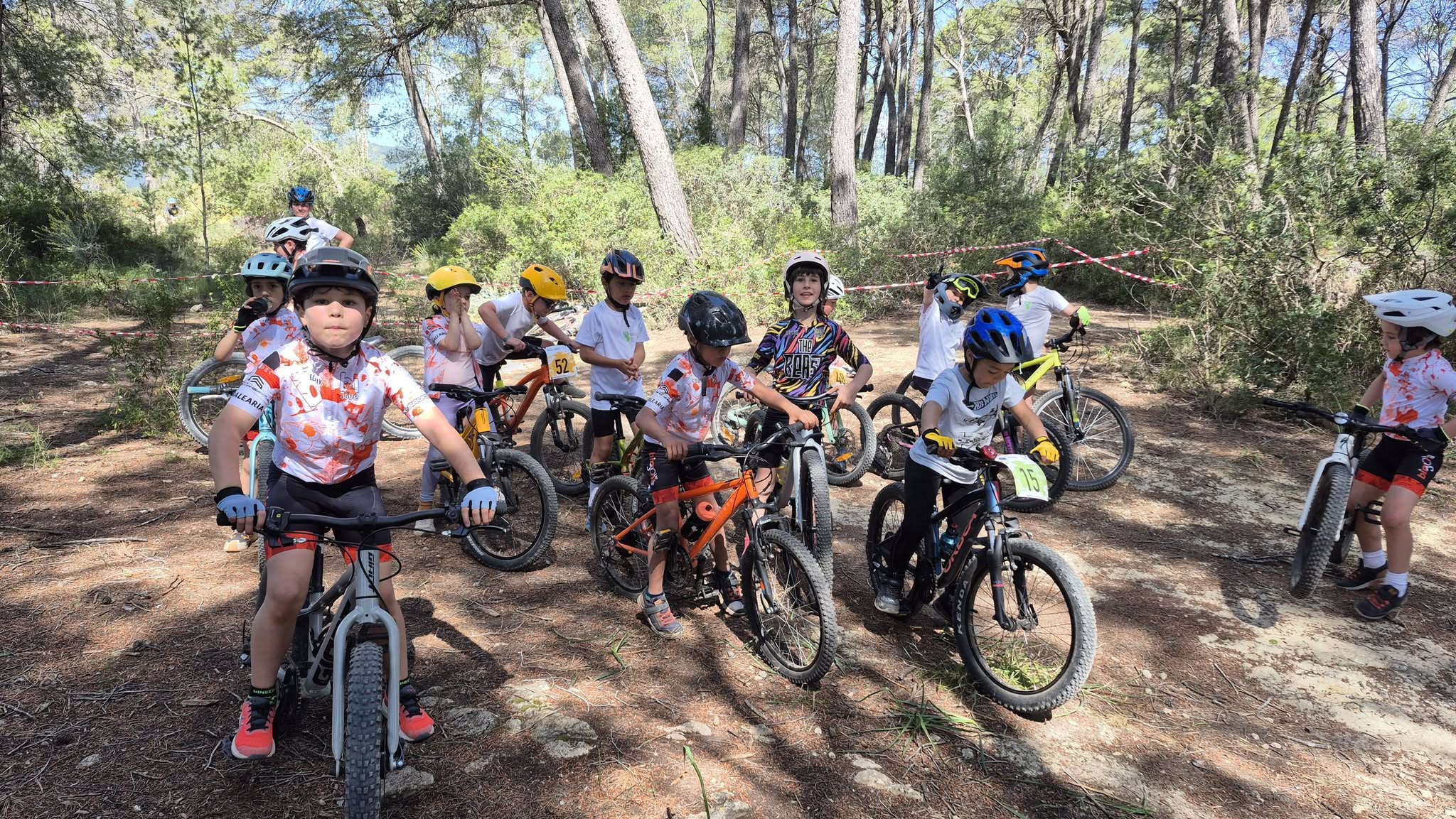 Grup de nins de l'escola Bimont Jove amb les bicicletes de muntanya en un pinar durant un entrenament